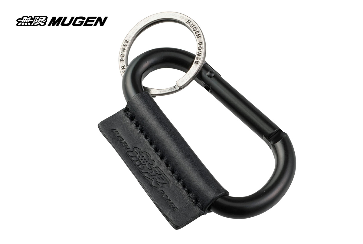 A close-up of the Mugen Power Carabiner Key Holder, showcasing its black Italian Buttero cowhide strap, silver aluminum carabiner with "MUGEN POWER" engraved, and double key rings, against a neutral background.