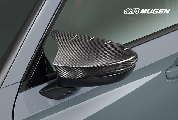 Pair of close-up MUGEN carbon fiber mirror covers with a fin shape and UV-cut finish, showing the Mugen logo.